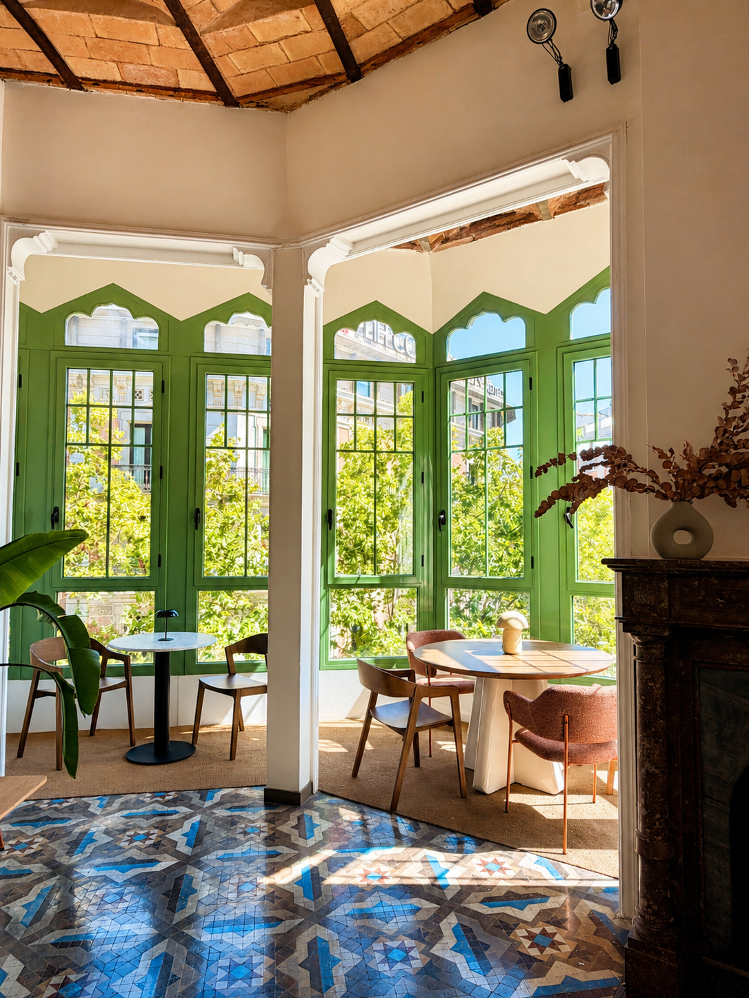 Bright studio interior with green arched windows, a wooden table, and a fireplace